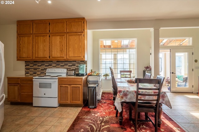 kitchen featuring tasteful backsplash, light tile patterned floors, electric stove, and a wealth of natural light