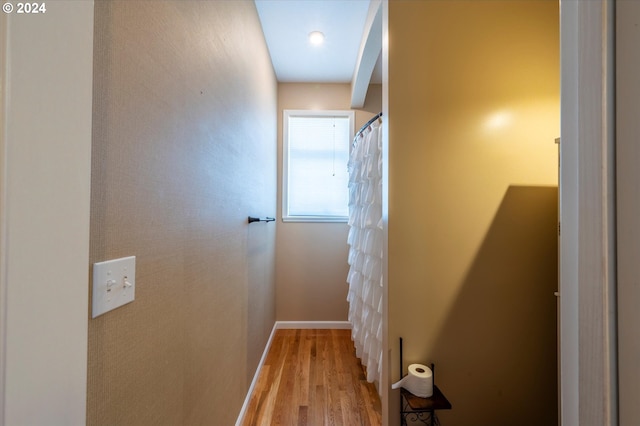 hall with baseboards and wood finished floors