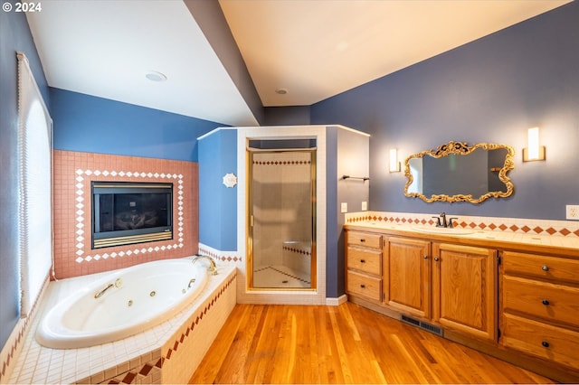 bathroom with hardwood / wood-style flooring, separate shower and tub, and vanity