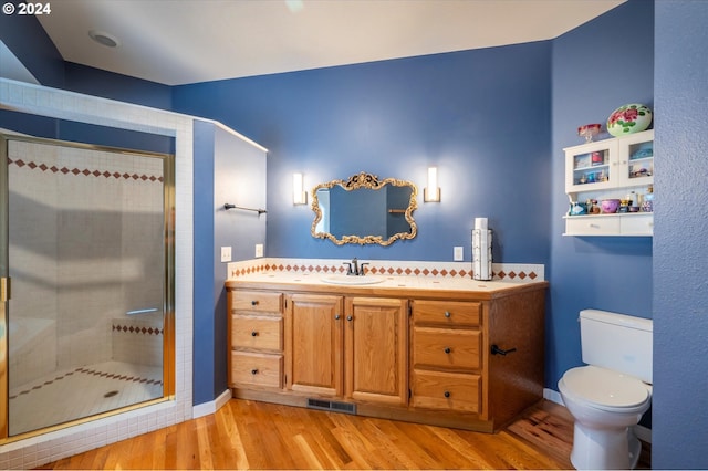 bathroom featuring hardwood / wood-style flooring, an enclosed shower, vanity, and toilet