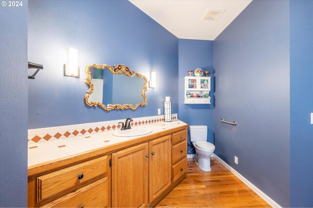 bathroom featuring toilet, vanity, and wood finished floors