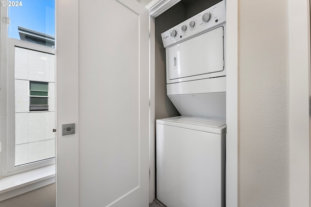 clothes washing area featuring stacked washer and dryer and plenty of natural light