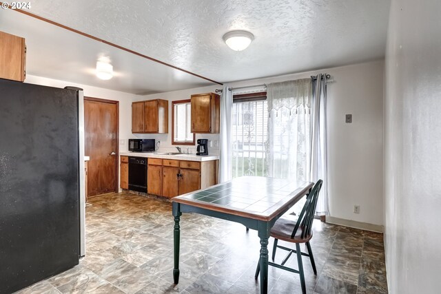 kitchen featuring a textured ceiling, light tile flooring, sink, and black appliances