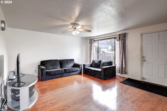 living room with a textured ceiling, wood-type flooring, and ceiling fan