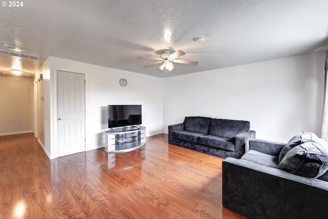 living room featuring light hardwood / wood-style flooring, ceiling fan, and a textured ceiling