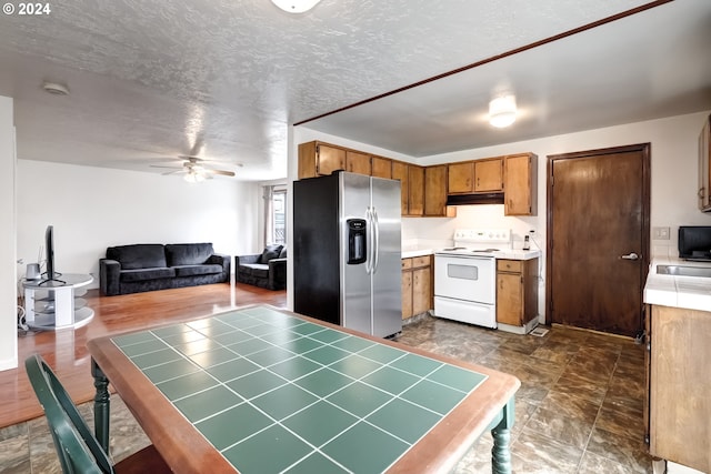 kitchen with tile counters, ceiling fan, dark tile flooring, white range with electric cooktop, and stainless steel refrigerator with ice dispenser