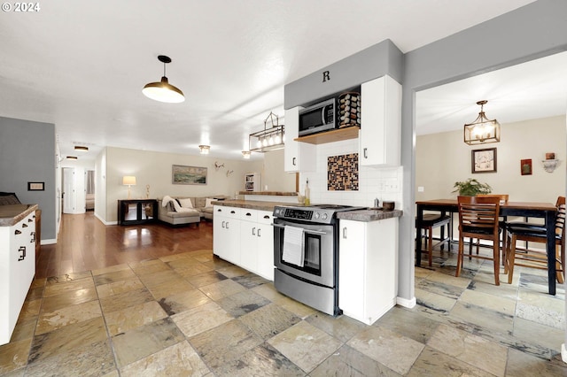 kitchen with hanging light fixtures, backsplash, appliances with stainless steel finishes, white cabinetry, and a notable chandelier