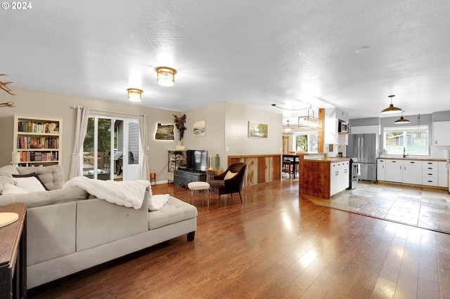 living room featuring light hardwood / wood-style floors, built in features, a textured ceiling, and sink