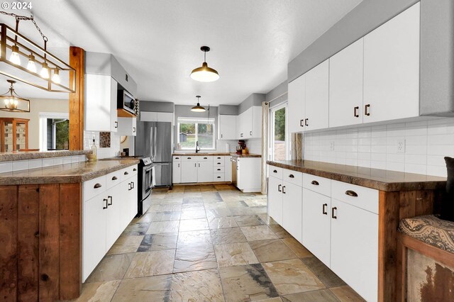 kitchen featuring tasteful backsplash, appliances with stainless steel finishes, sink, pendant lighting, and white cabinets