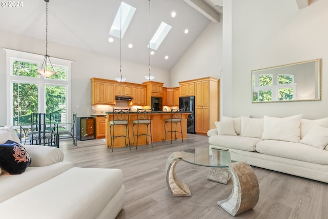 living room featuring beam ceiling, light wood-type flooring, a skylight, and high vaulted ceiling