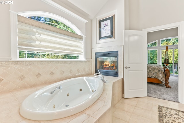 bathroom with tile patterned flooring, tiled bath, lofted ceiling, and a tiled fireplace