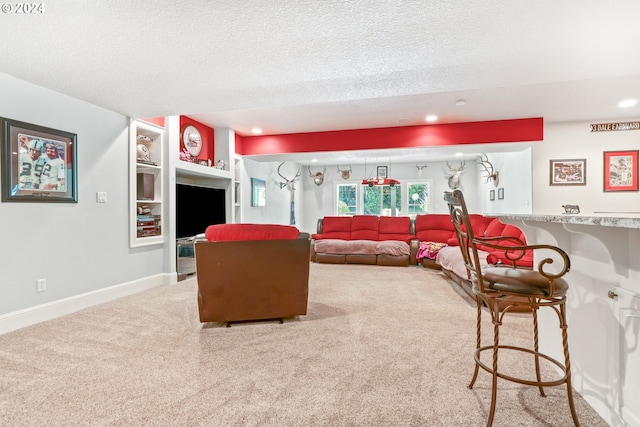 living room featuring built in shelves, carpet floors, and a textured ceiling