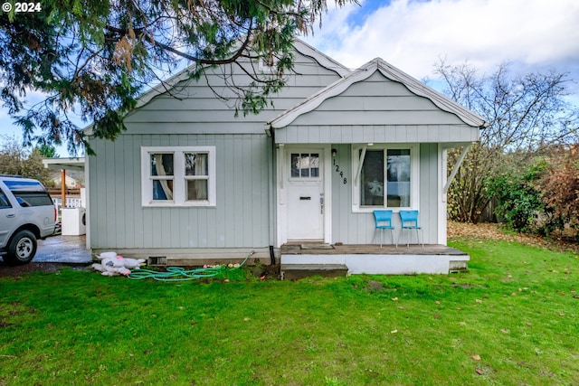 bungalow featuring covered porch and a front yard