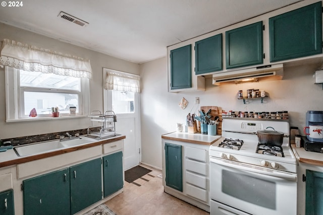 kitchen featuring ventilation hood, green cabinetry, gas range gas stove, and sink