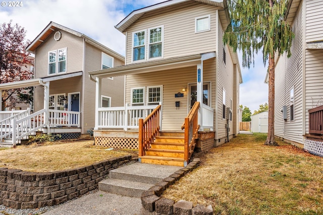 front of property with a porch, a front lawn, and a storage shed