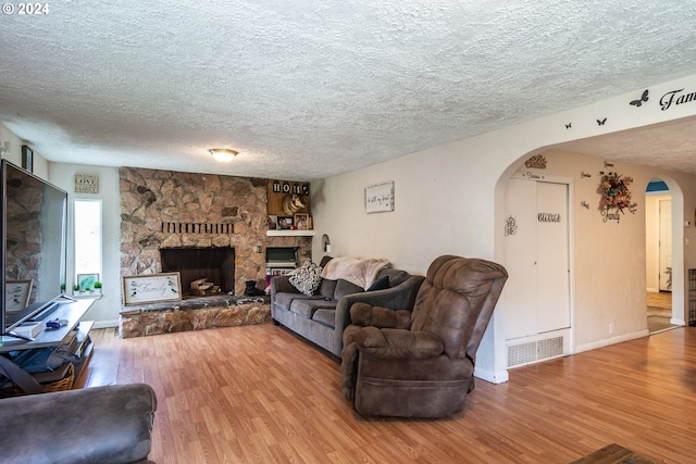 living room with a textured ceiling, hardwood / wood-style floors, and a fireplace