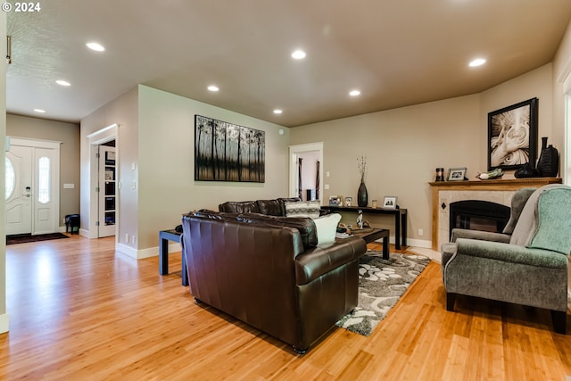 living room featuring light wood-style flooring, a fireplace, baseboards, and recessed lighting