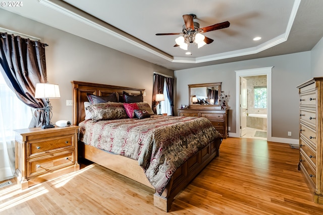 bedroom with baseboards, a tray ceiling, light wood-type flooring, and recessed lighting