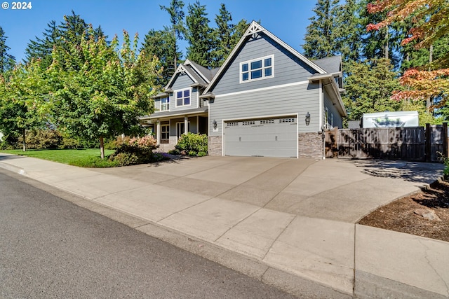 craftsman-style home with an attached garage, stone siding, fence, and concrete driveway