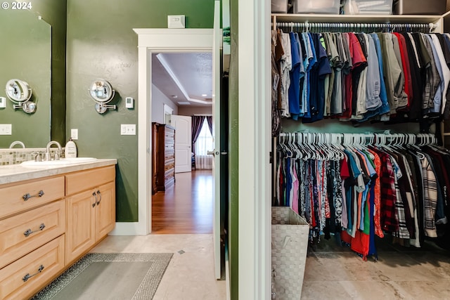 bathroom with a spacious closet, vanity, and baseboards