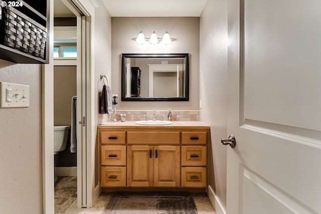 bathroom with backsplash, toilet, and vanity