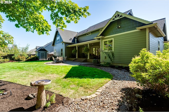 rear view of property featuring an outbuilding, fence, a yard, a patio area, and a shed