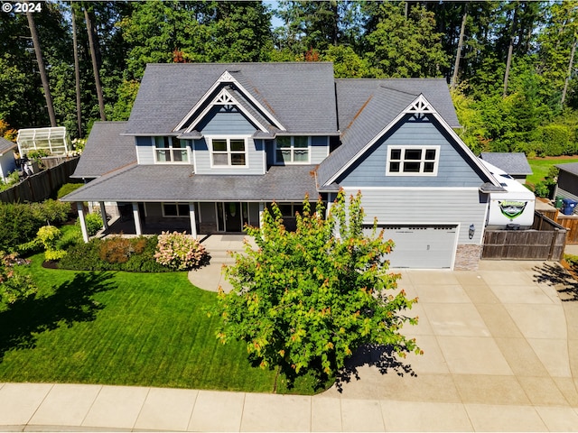 view of front facade with driveway, a shingled roof, fence, a front lawn, and a porch