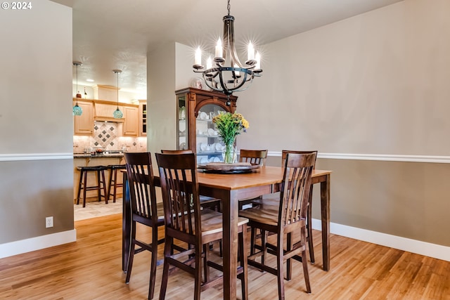 dining space with light wood-style floors, baseboards, and an inviting chandelier