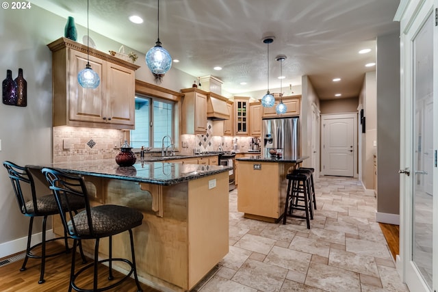 kitchen featuring stainless steel appliances, a breakfast bar, a peninsula, a sink, and backsplash