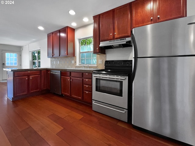 kitchen featuring stainless steel appliances, dark hardwood / wood-style flooring, kitchen peninsula, and a wealth of natural light