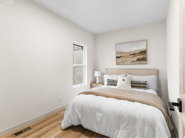 bedroom with visible vents, baseboards, and wood finished floors