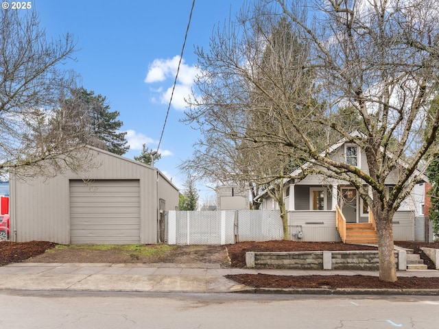 view of front of home with an outbuilding, driveway, a gate, a detached garage, and fence