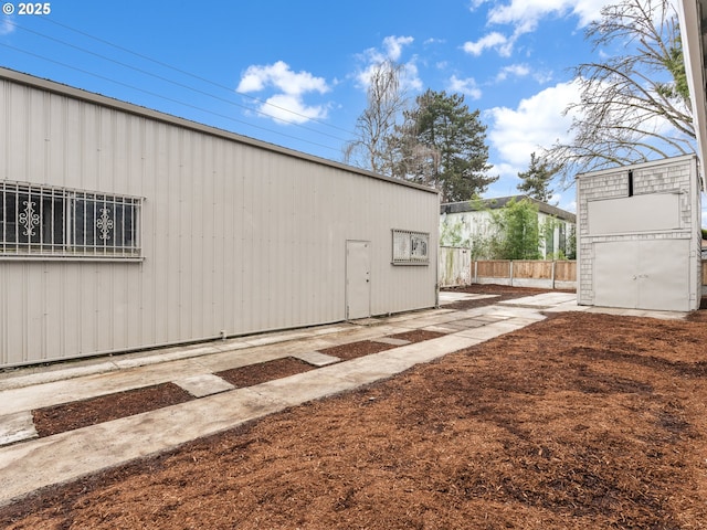 view of side of home featuring a patio area, an outdoor structure, and fence