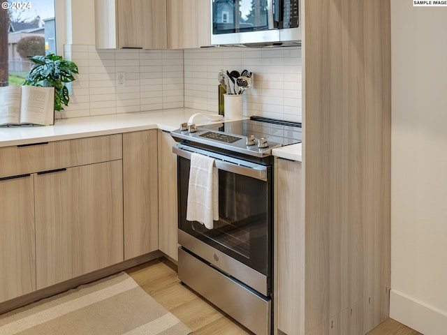 kitchen with light brown cabinets, backsplash, stainless steel electric range oven, and light wood-type flooring