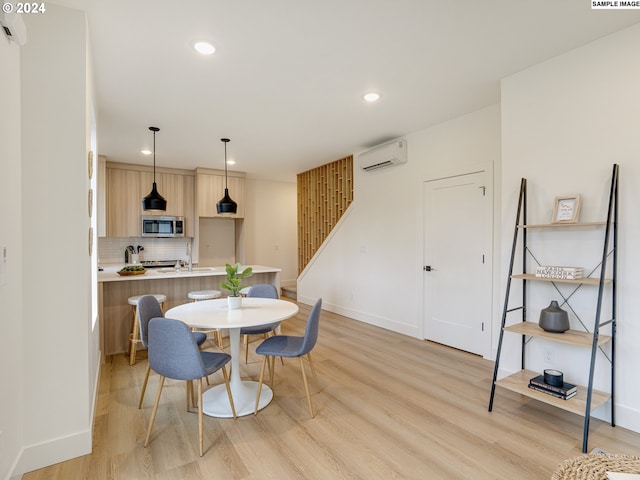 dining space with a wall mounted air conditioner and light hardwood / wood-style flooring