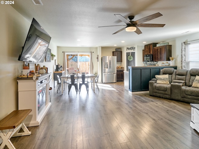 living room featuring ceiling fan, plenty of natural light, light wood-type flooring, and a textured ceiling