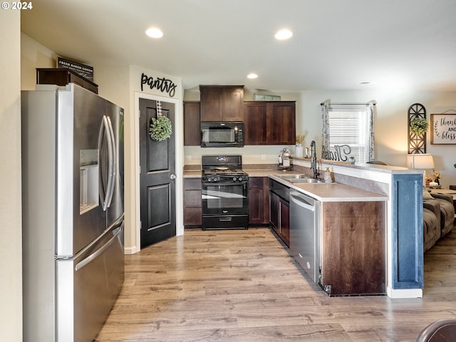 kitchen with black appliances, sink, dark brown cabinets, and light hardwood / wood-style flooring