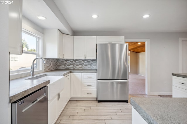 kitchen featuring backsplash, stainless steel appliances, light hardwood / wood-style floors, and white cabinetry