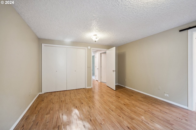 unfurnished bedroom with a textured ceiling, a closet, and light wood-type flooring