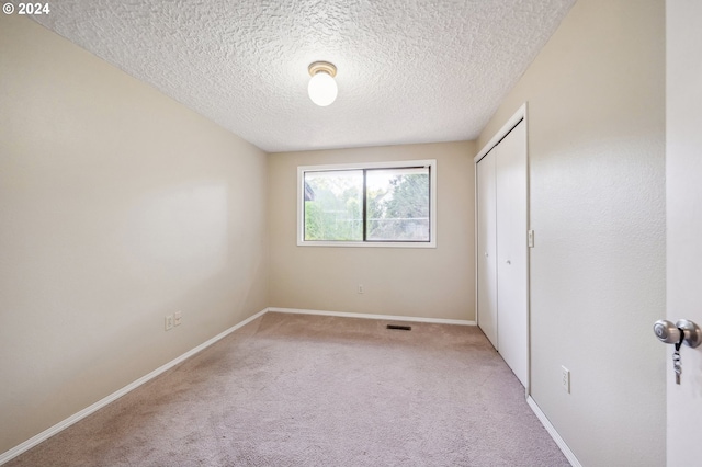 carpeted empty room featuring a textured ceiling