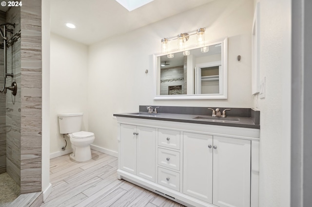 bathroom featuring vanity, toilet, wood-type flooring, and a tile shower