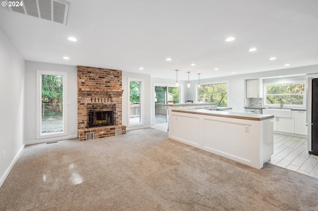 kitchen with a wealth of natural light, a center island, decorative light fixtures, and a brick fireplace