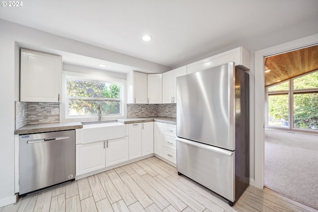 kitchen with plenty of natural light, light wood-type flooring, appliances with stainless steel finishes, and white cabinetry