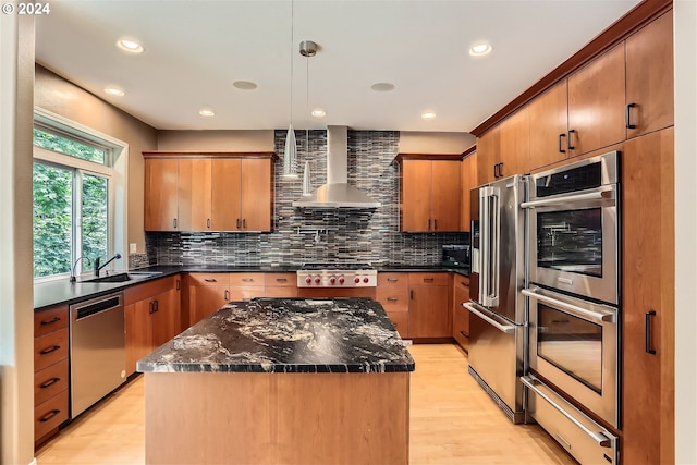 kitchen featuring wall chimney range hood, light wood-type flooring, stainless steel appliances, and backsplash