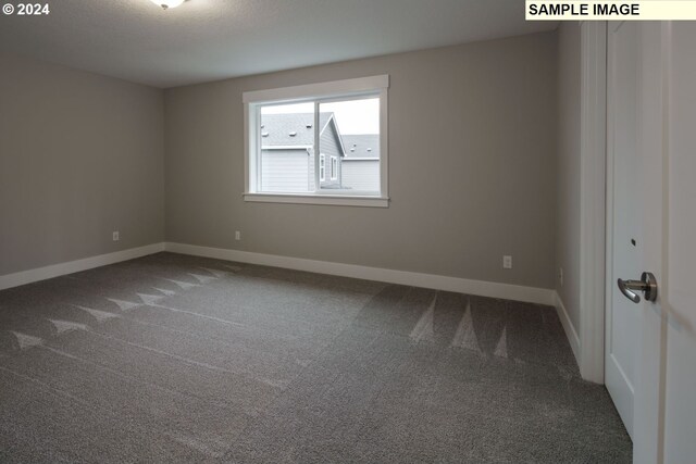 unfurnished room with dark colored carpet