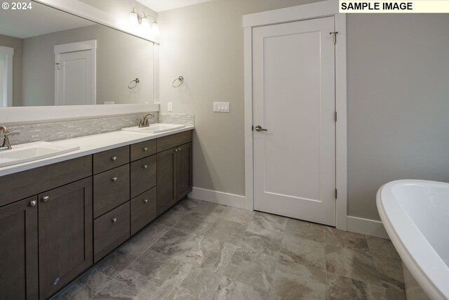 bathroom featuring dual bowl vanity, tasteful backsplash, tile floors, and a bath to relax in