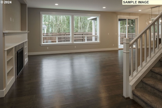 unfurnished living room featuring dark hardwood / wood-style flooring, a fireplace, and an inviting chandelier