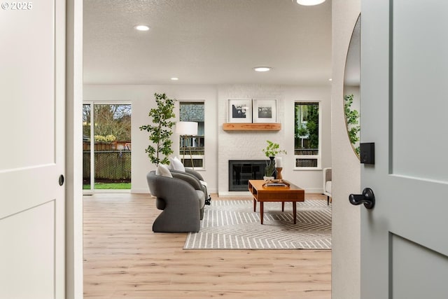 living area with recessed lighting, a fireplace, a textured ceiling, and wood finished floors