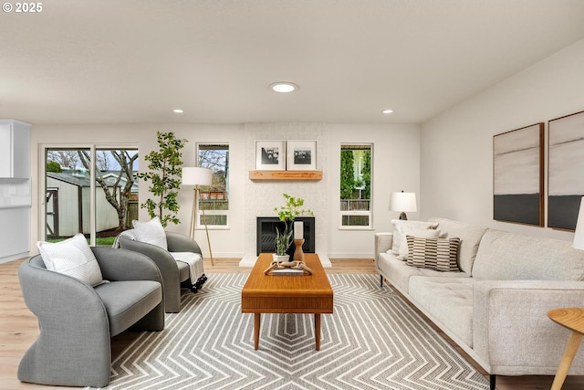 living room featuring recessed lighting, a fireplace, baseboards, and wood finished floors