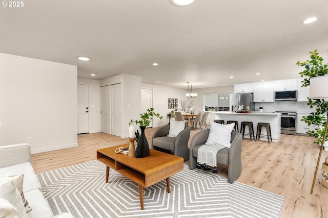 living room featuring recessed lighting, light wood-type flooring, baseboards, and a chandelier